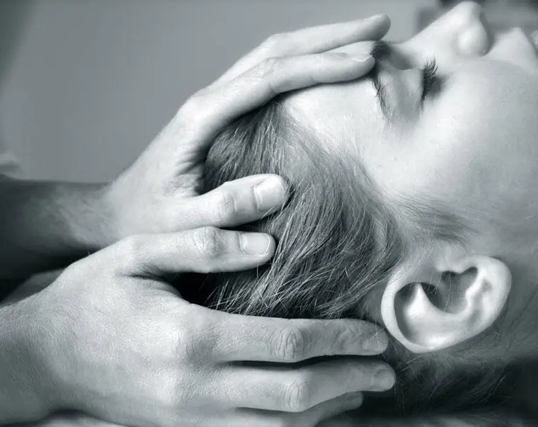 Mains posées autour du crâne lors d’une consultation d’ostéopathie